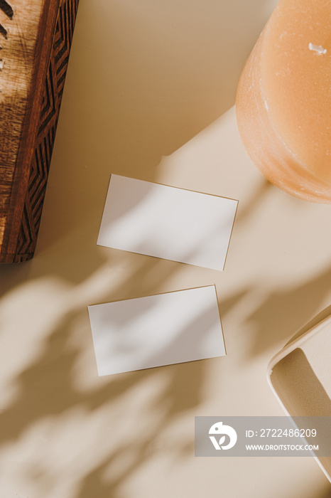 Blank paper sheet cards with mockup copy space, wooden casket and candle with sunlight shadow on beige background. Flat lay, top view minimal business brand template