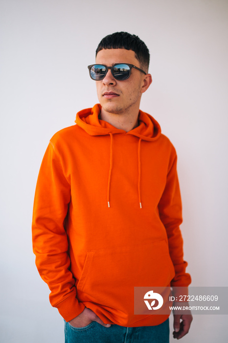 City portrait of handsome hipster guy wearing orange blank hoodie or hoody with space for your logo or design. Mockup for print