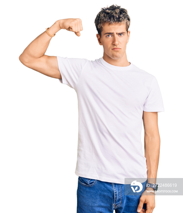 Young handsome man wearing casual white tshirt strong person showing arm muscle, confident and proud of power