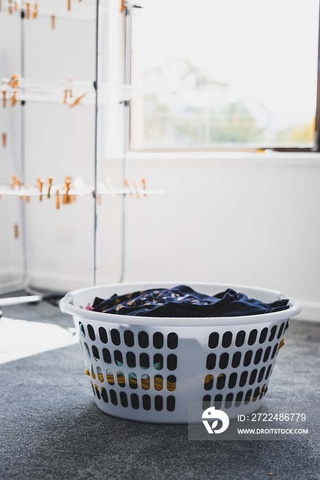 laundry basket with clean laundry to be hung on clothes airer next to it, household chores and daily life routine