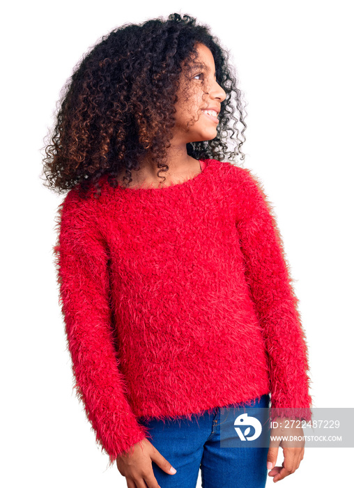 African american child with curly hair wearing casual winter sweater looking away to side with smile on face, natural expression. laughing confident.