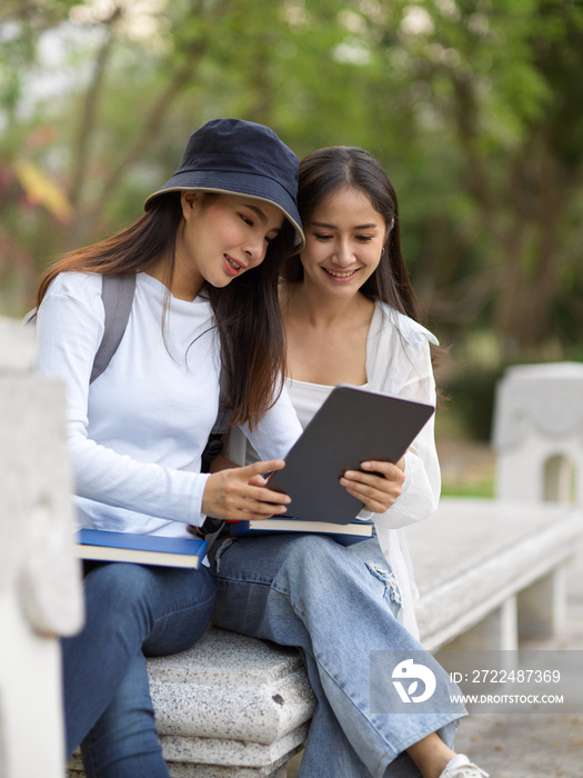 Female university students reading to prepare for up coming their exam at park in university