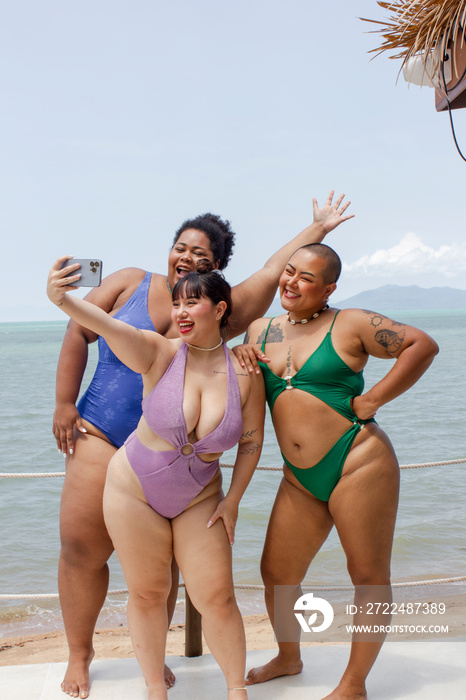 Group of cheerful women taking selfie on beach