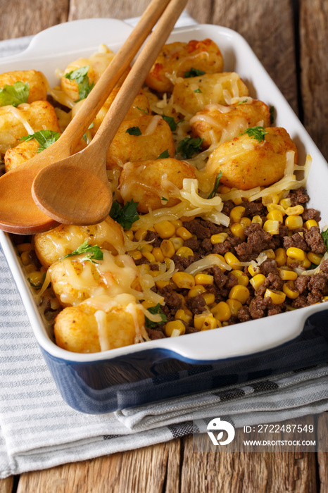 Baked Tater Tots with ground beef, corn and cheese close-up on the table. vertical