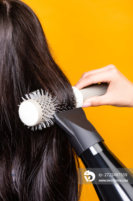 Cropped view of hairdresser using hairdryer and brush isolated on yellow