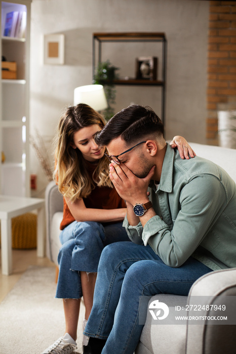 Young man having a problem. Wife comforting her sad husband.