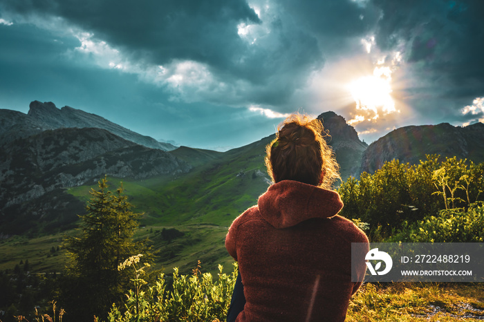 Sporty woman in outdoor jacket watches beautiful mountain scenery at sunset. Falzarego pass, Dolomites, South Tirol, Italy, Europe.