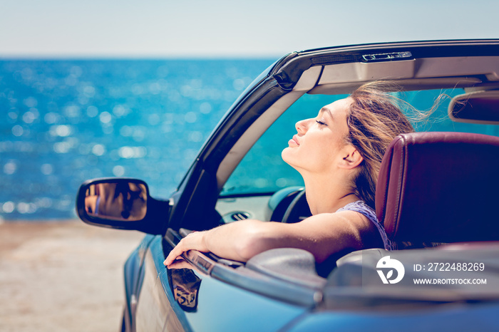 Happy and carefree woman in the car on the beach