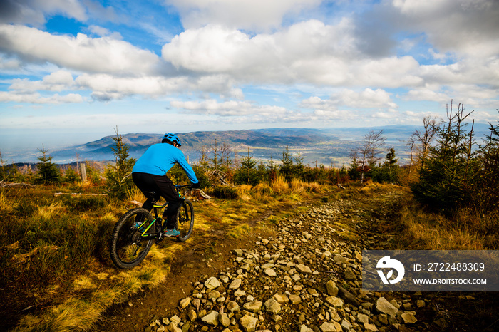 Mountain biker cycling in autumn mountains forest landscape. Man cycling MTB flow trail track. Outdoor sport activity.