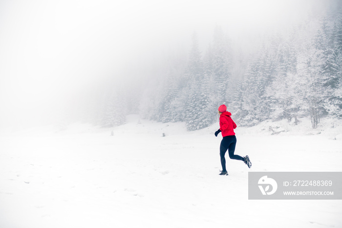 Girl trail running on snow in winter mountains