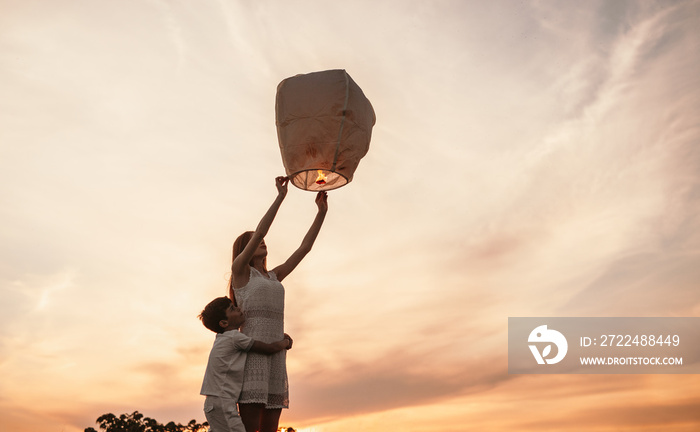 Teen girl with little brother releasing sky lantern