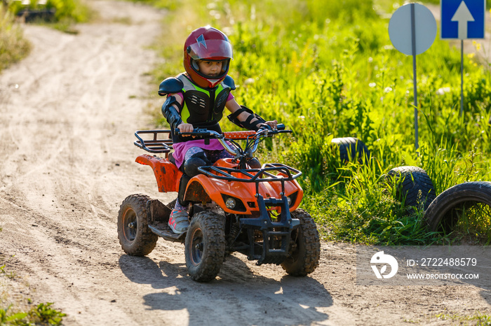 Little girl riding ATV quad bike in race track