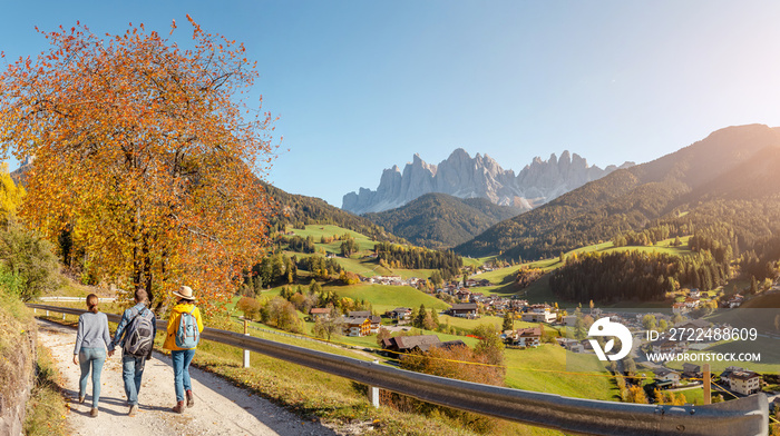 Active three friends travel Santa Magdalena village in Funes Valley, Italian Alps