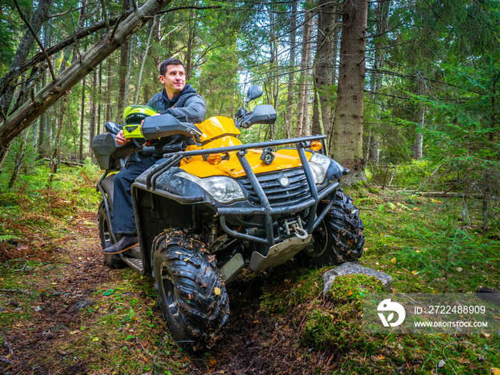 A man travels in an all-terrain vehicle. Off road ATV. Wild nature. A man sits on the all-terrain vehicle. Yellow ATV.