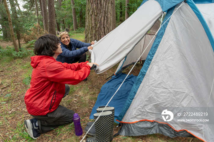 Mother and son setting up tent in forest