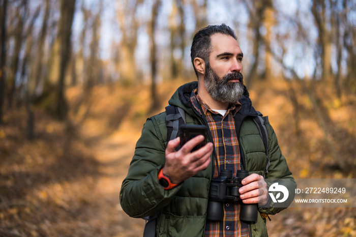 Image of hiker using phone while spending time in nature.