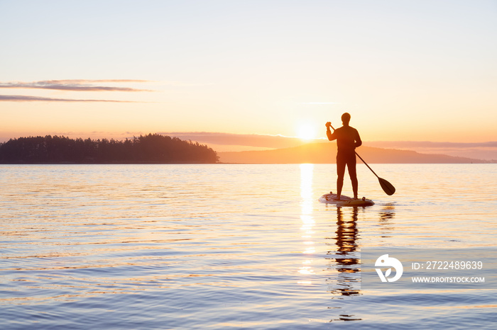 Adventurous Caucasian Adult Woman on a Stand Up Paddle Board is paddling on the West Coast of Pacific Ocean. Sunny Sunrise. Victoria, Vancouver Island, BC, Canada.