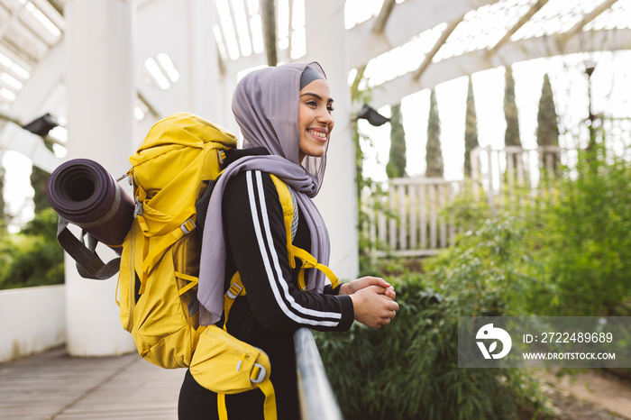 backpacking muslim woman travelling. Smiling young woman tourist wearing Hijab in nature landscape looking around