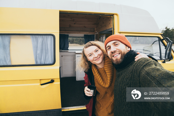 Young happy couple taking selfie in front of their camper van