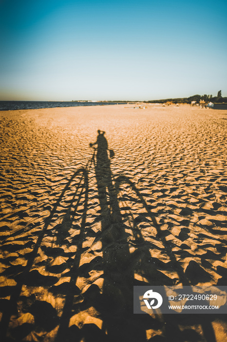 Summertime adventures during mountain bike riding on the sand beach. Concept photo of bike riding on the seaside. Long shadow on a sand beach