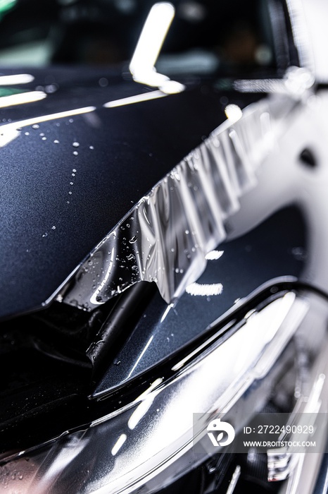 Hood of a modern car during the application of a tranparent protective film in a car detailing studio