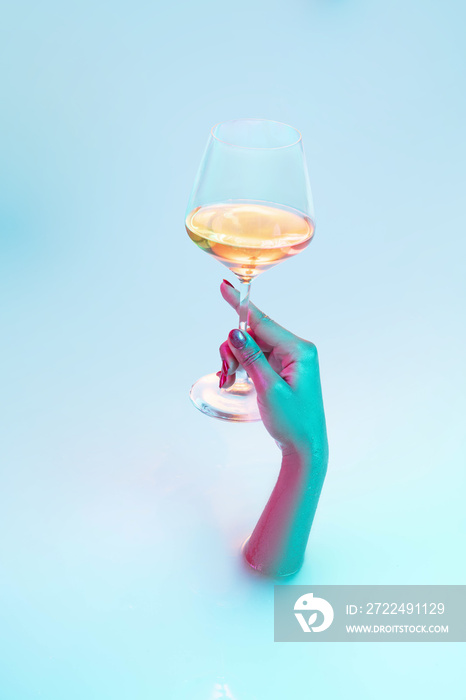 Cheers, party. Close up female hand gesturing from the milk bath with soft white glowing in neon light. Copyspace for advertising. Holding glass of white wine, alcohol. Modern neoned colors.