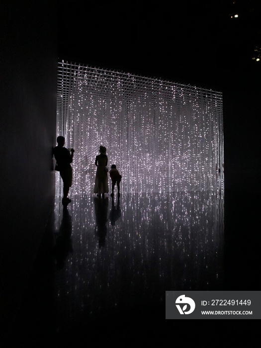 Silhouette of a man with woman and child on abstract background space dark room silhouettes light stars led wall