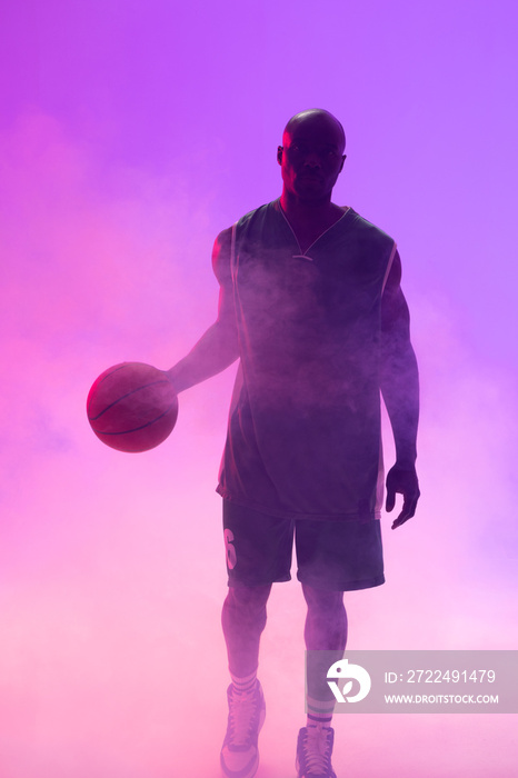 Image of african american basketball player with basketball and smoke on purple background