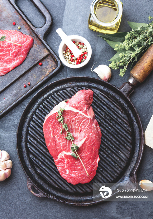 Fresh raw meat. Beef Tenderloin and marbled beef steaks on grill pan and frying board with seasoning, black background top view