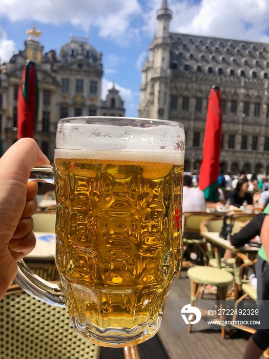 Tourist is holding a full beer glass in Brussels Grand Place