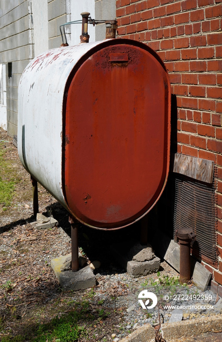 Older home heating oil fuel tank standing on concrete slabs.