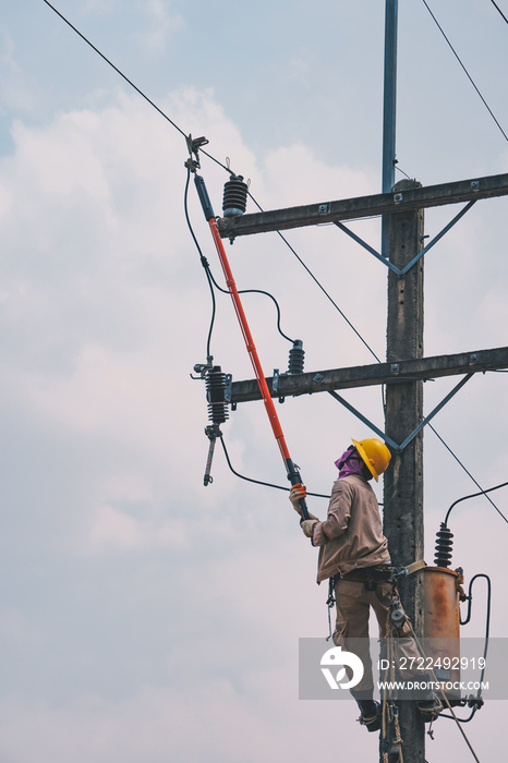 The power lineman use clamp stick (insulated tool) to closing a transformer on energized high-voltage electric power lines. The power lineman must be trained because it is a risky job.