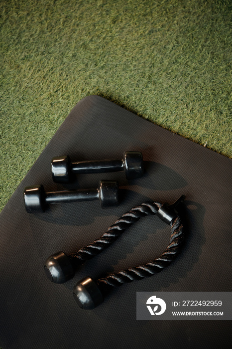 Dumbbells and triceps rope on gym floor, view from above