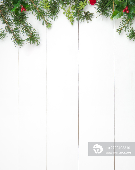 Creative Christmas layout. Fir twigs and red pompons. White wood background whit copy space. Border arrangement. Flat lay top view.