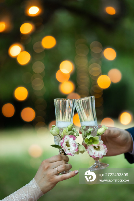 Wedding party concept. Symbol of love and commitment. Newlyweds cheers and toasting together. Orange lights bokeh background.