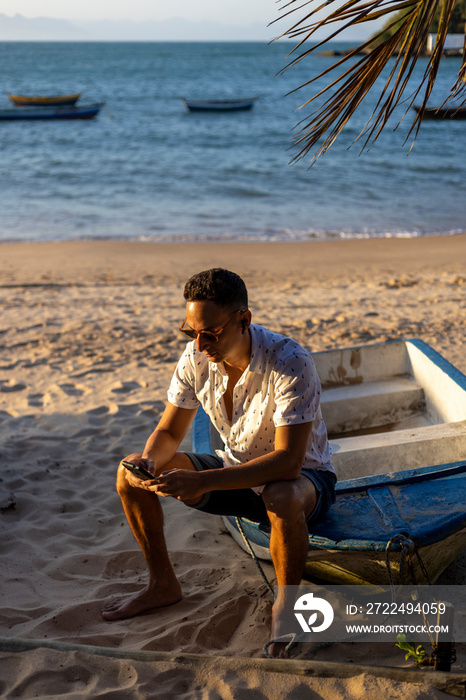 Man sitting at beach and using smart phone