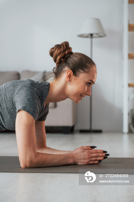 Close up view. Young woman with slim body type and in yoga clothes is at home