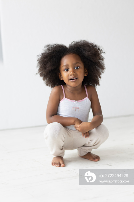 Portrait of girl squatting on wooden floor