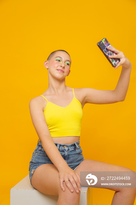 Studio shot of girl with neon colored make-up taking selfie