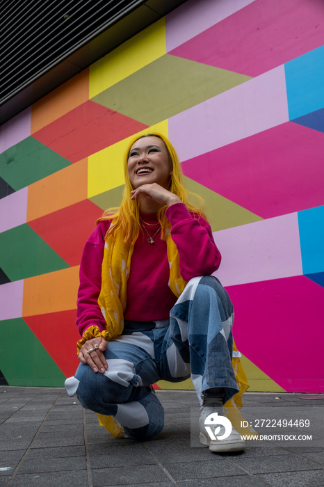 Young woman with yellow hair crouching outdoors