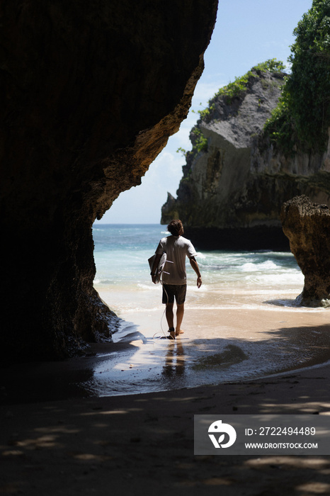 Young man surfer with surfboard on the ocean, uluwatu surfspot.