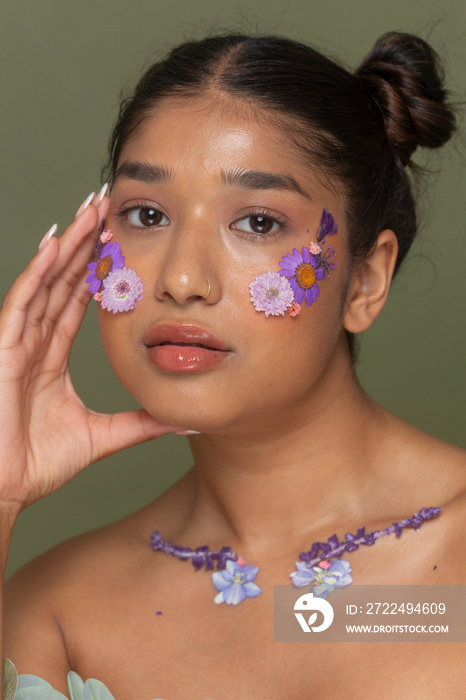 Studio portrait of woman with flowers on face and collarbone