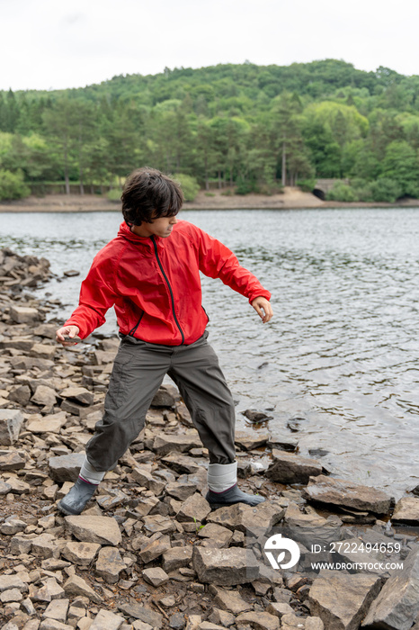 Young man skipping stones in lake