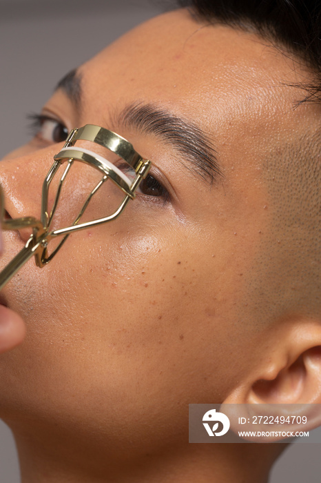 Close-up of person curling eyelashes with curler