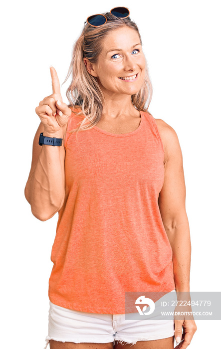 Middle age fit blonde woman wearing casual summer clothes and sunglasses pointing finger up with successful idea. exited and happy. number one.