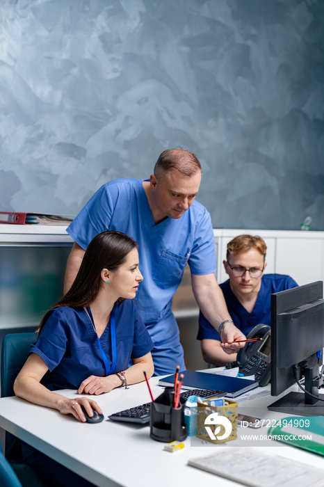 Three doctors are working on medical expertise while sitting at desk in front of computer.