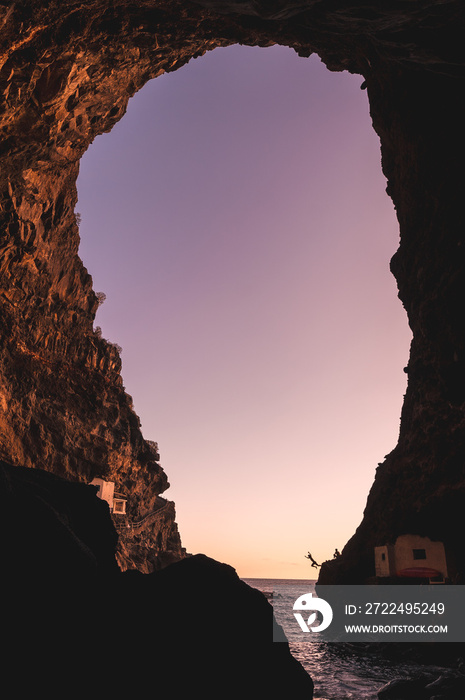 Sunset from inside the cave of the town of Poris de Candelaria on the north-west coast of the island of La Palma, Canary Islands. Spain. And young people jumping into the water