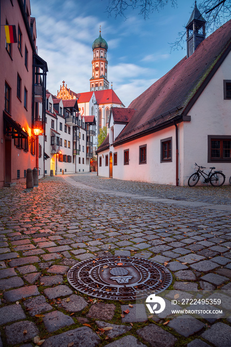 Augsburg, Germany. Cityscape image of old town street of Augsburg, Germany with the Basilica of St. Ulrich and Afra at autumn sunset.