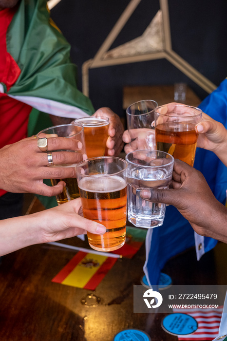 Friends dressed in national flags for world cup competition drinking beer