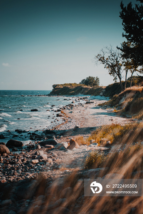 A perfect summer day at the wild natural beach with beautiful ocean views and colorful evening sunset light. A Tropical looking empty and lonely stone beach. Fehmarn at the German Baltic Sea in German